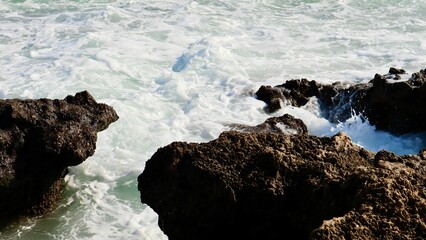 Foamy sea water between porous rocks