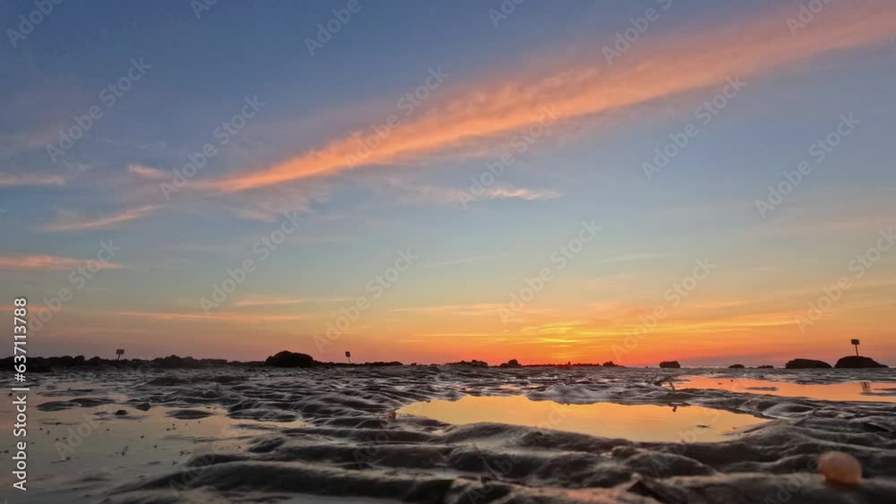 Wall mural time lapse of sunset cloudy sky over shoreline water with silhouette people