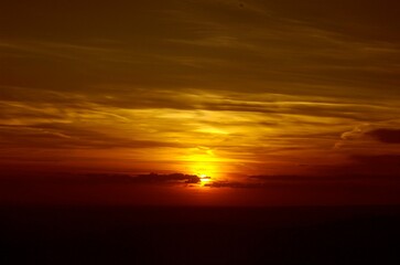 Vibrant cloudy sky at sunset in shades of yellow and red.