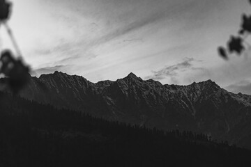 Grayscale cinematic shot of snowcap mountaintops against gloomy sky in Himachal Pradesh, India