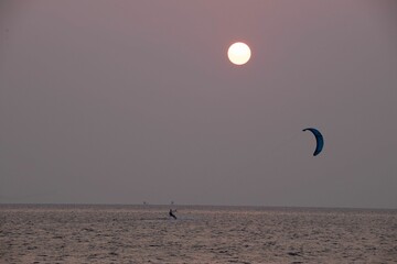 two kite surfers glide across the ocean under the sun