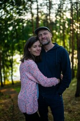 Young Caucasian couple embracing while standing in a lush, green forest