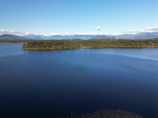 Landscape of the sea surrounded by greenery under a blue sky and sunlight