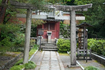 Stone pathway with a stone arch leading to a red building in a park