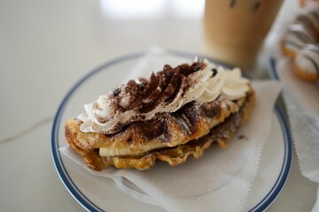 Closeup of a white plate with two slices of French toast, each topped cream and cocoa