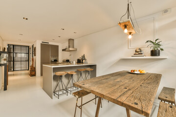 a kitchen and dining area in a modern apartment with white walls, wood flooring and an island table surrounded by metal stools