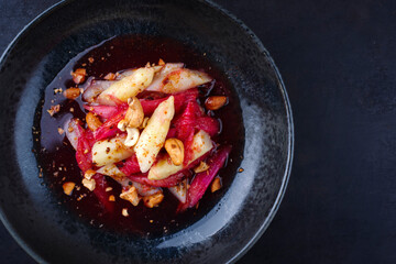 Deutscher Rhabarber Spargel Salat mit Cashew Nüssen in Himbeersauce serviert als Draufsicht in einer Nordic Design Schale mit Textfreiraum rechts