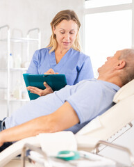 Obraz premium Adult woman medic makes notes in documents in medical room