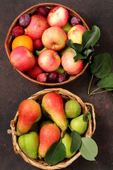 Apples, pears and plums in baskets on a sunny wooden table, thanksgiving background, village harvest, healthy natural food concept, detox diet and body cleansing, screen banner, cafe, 