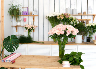 Florist's workplace in flower shop with bouquet of pink roses and wrapping paper for creating bouquets.
