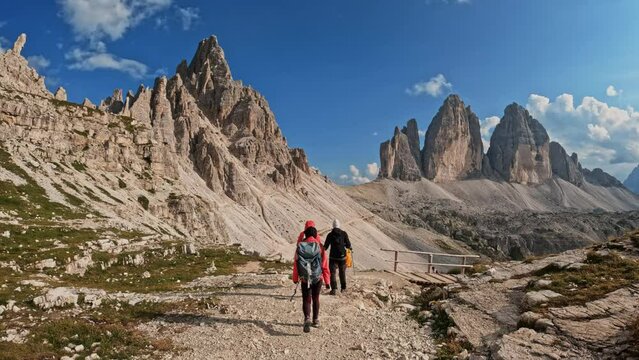 Active people with backpacks hiking trail path and climbing Tre Cime di Lavaredo Dolomites mountain. Group of friends summer adventure journey in nature. Travel exploring Alps, Dolomites, Italy