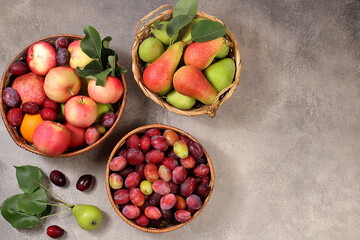 Apples, pears and plums in baskets on a sunny wooden table, thanksgiving background, village...