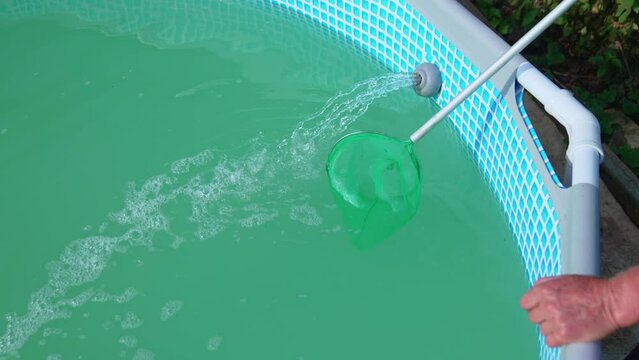 hands clean the pool with midge, and the water in the pool is cleaned by a pump
