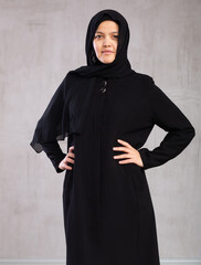 Portrait of young calm woman in hijab posing against background of studio
