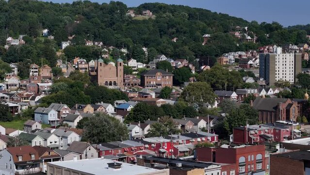 A rotating parallax aerial view of a small Pennsylvania town. Church and apartment building in the distance, row houses below. Pittsburgh suburbs.  	