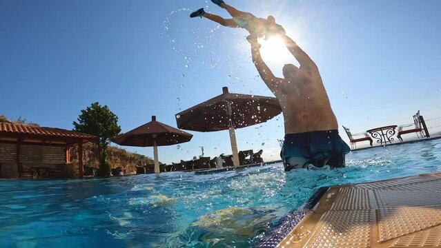 Father and son in the pool in summer playing enjoying and lifting him up on vacation