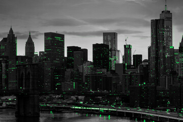 Green lights shining in black and white night time cityscape with the Brooklyn Bridge and buildings of Manhattan in New York City