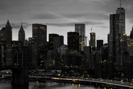 Yellow lights shining&nbsp;in black and white night time cityscape with the Brooklyn Bridge and buildings of Manhattan in New York City
