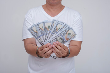 An anonymous man in handcuffs holding cash. Concept of financial crimes, or bailout money.