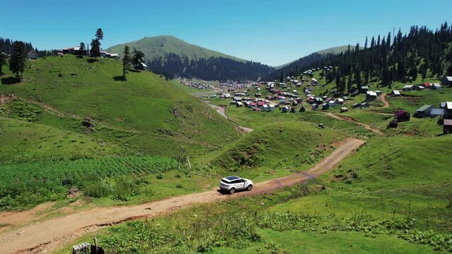 Car driving through a mountain village. SUV on country road.