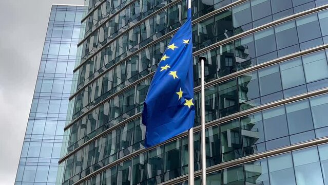 European Union flags flutter in wind against glass building facade background, Brussels, Belgium, Europe, August 5, 2023. High quality 4k footage