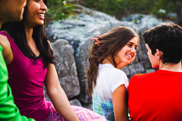 Two young couples sit on a sandstone cliff in the evening