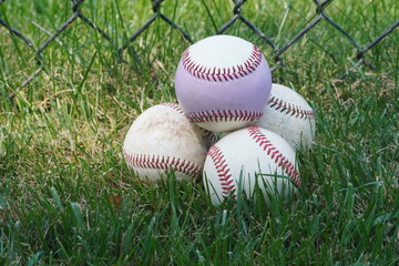 Closeup of Baseball Pile in Grass by Cyclone Fence 