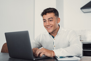 Side view handsome young businessman in eyewear working with computer remotely, sitting at wooden...