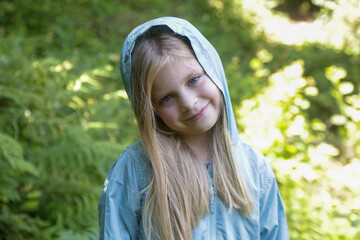 Candid headshot of adorable little girl wearing windbreaker jacket in the forest, spending time in the nature, outdoors experience in the countryside