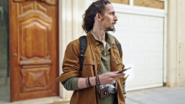 Young hispanic man tourist using smartphone looking watch at street