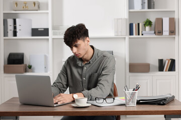 Young man working at white table in office. Deadline concept