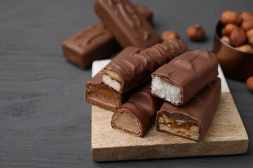 Pieces of different tasty chocolate bars on grey wooden table, closeup. Space for text