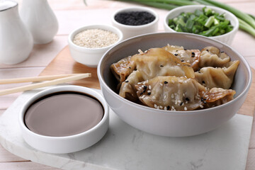 Delicious gyoza (asian dumplings) with sesame and soy sauce on table, closeup