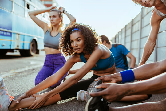 Young and diverse group of people stretching before going on a jog and running together in the city