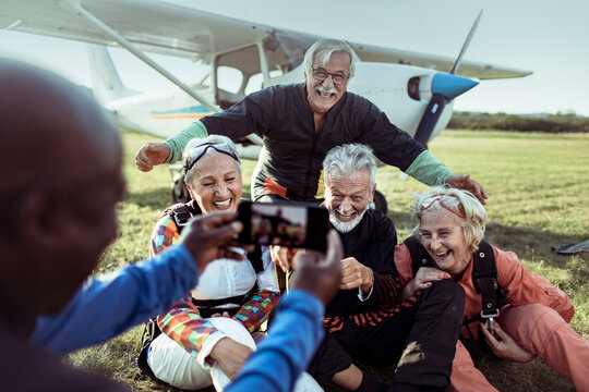 Group of senior people taking a photo after skydiving on a field