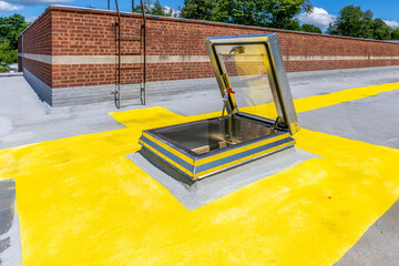Roof hatch for access to roof with a built in skylight on a spray foam roof with painted yellow...