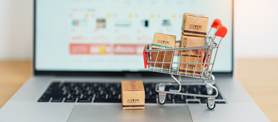 Boxes with shopping cart on a laptop computer. online shopping, Marketplace platform website, technology, ecommerce, shipping delivery, logistics and online payment concepts - obrazy, fototapety, plakaty