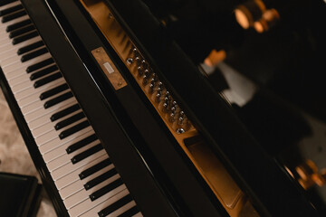 The keyboard of a very old abandoned piano is covered with dust, some keys have dropped, some are...