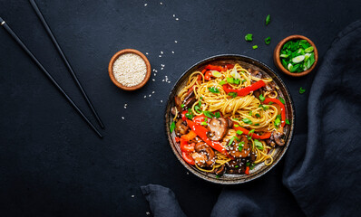 Stir fry noodles with vegetables: red paprika, champignons, green onion and sesame seeds in ceramic...