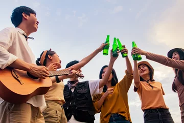 Foto op Aluminium Asian gang of guys and girls playing guitar singing toast over cold beers smashing beer bottles and laughing happily come join the friendship goodwill of close friends during the event camp party. © ฺฺฺBoonterm