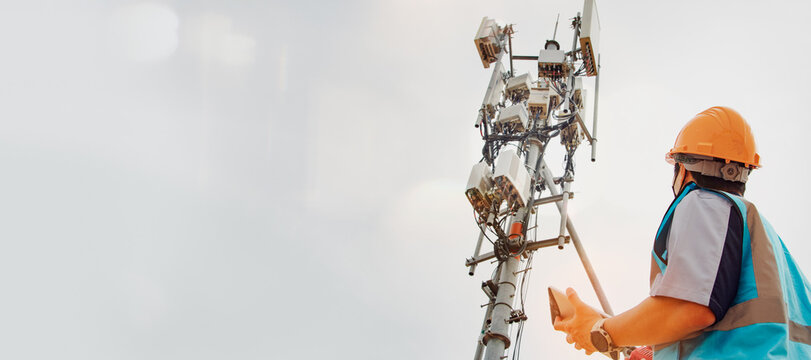 Asian male engineer safety helmet works in the field  high rise building inspecting telecommunication tower structures setting up electronic power grids and maintaining 5G networks for safety reasons.