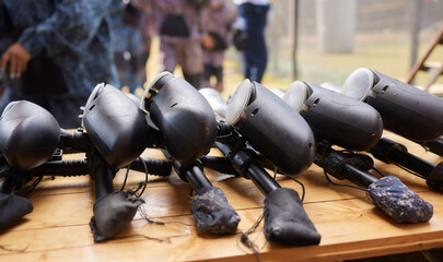 Close up of paintball gun, special balls and protective mask, equipment for playing paintball on a wooden table, action game concept.