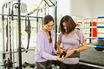Female trainers advise and support exercise women maintain their health helping them wear...