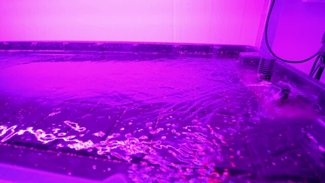 Slow rotating shot of water entering the vertical farm machinery under fluorescent lighting
