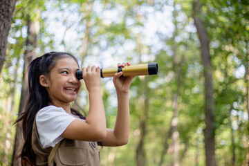 Happy Little Asian girls looking ahead and smiling child with the binoculars in the park. Travel...