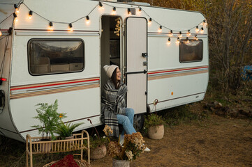 Caucasian woman sits in a van on a warm autumn day. Travel in a camper.