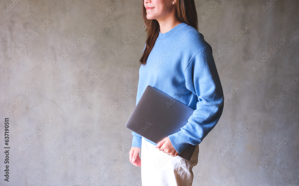 Wall mural Closeup image of a young woman holding laptop computer