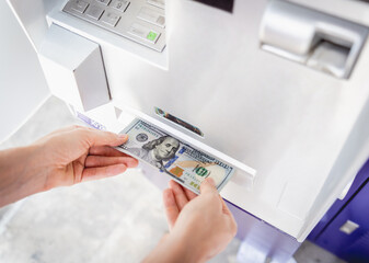 Young woman holding money in her hands after withdrawing the cash at the ATM