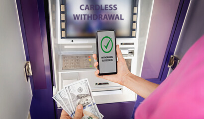 Young woman using the smart phone for cardless withdrawing the cash near the ATM