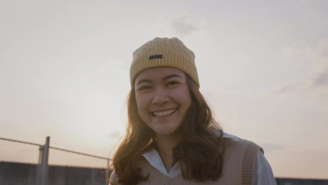 Young Gen Z Girl Asia People Curly Brown Hair, Face, Eye Smile In Blue Sky Sun Light Lens Flare. Teen Urban City Life Happy Joy Of Future Hope Enjoy Warm Time Relax Sunset. Good Mental Health Teenage.